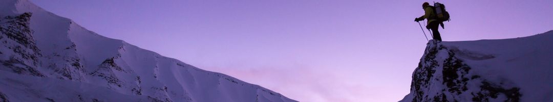 Mann auf schneebedecktem Berg vor violettem Himmel