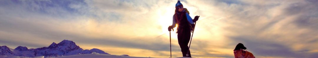 Person bei Sonnenaufgang mit Trekkingstöcken