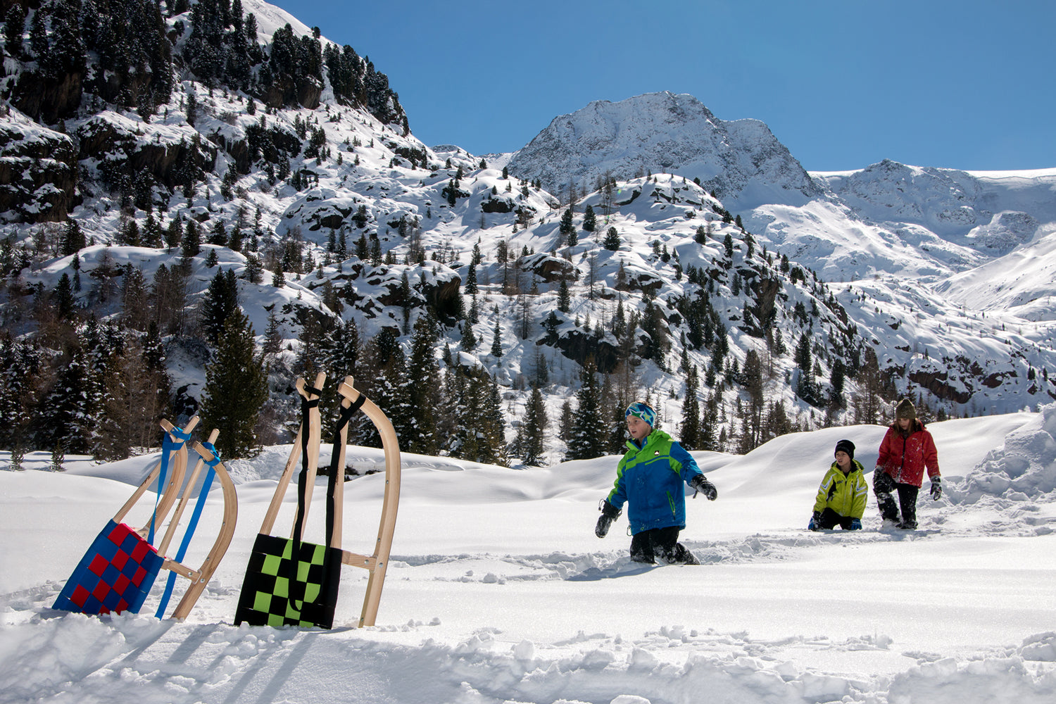 zwei Kathrein Tourenrodel Schüler mit Gurtsitz (90 cm - 6-10 Jahre) im Vordergrung, hinen 3 Personen im Schnee