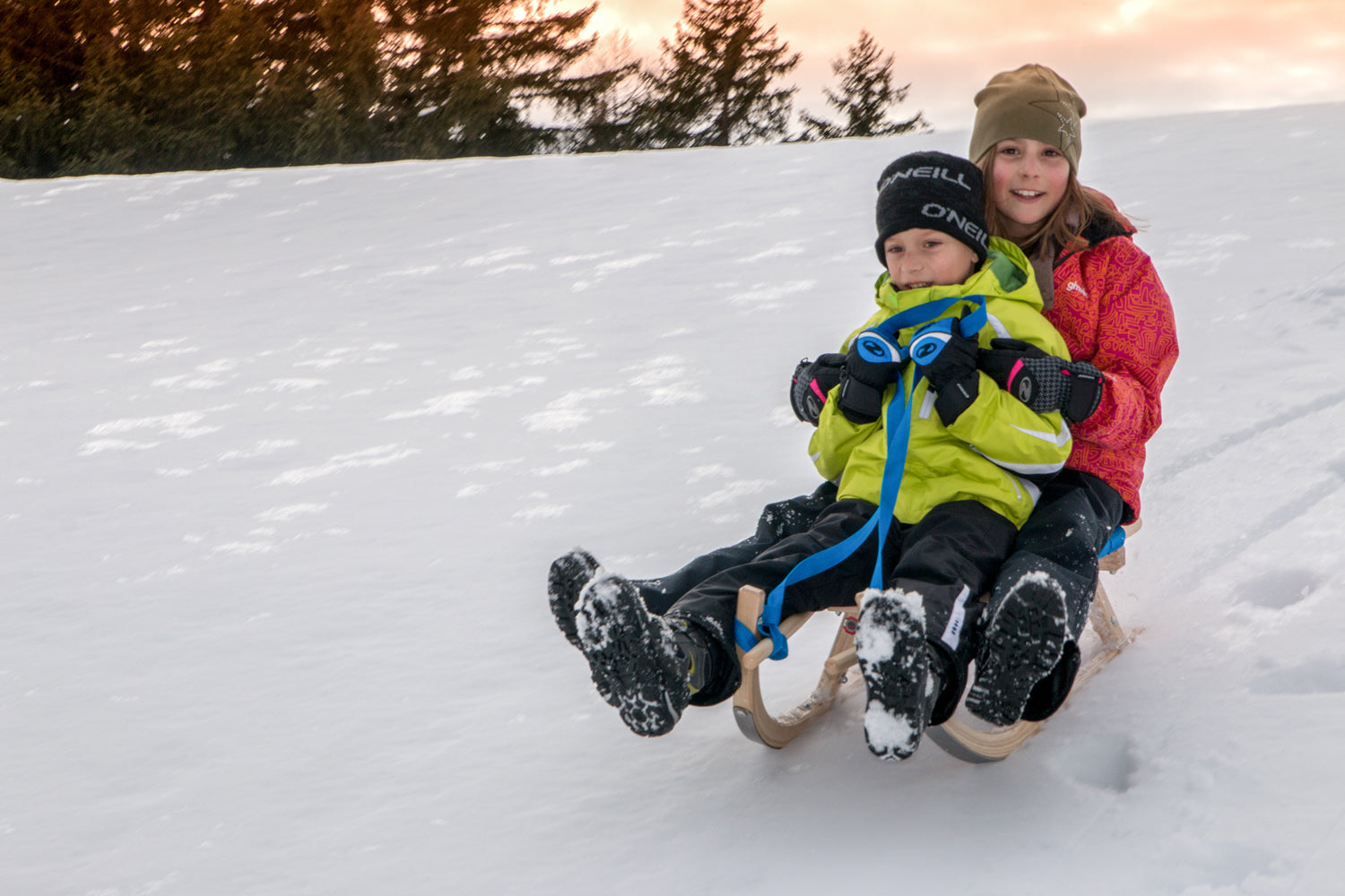 Mann und Kind rodeln einen Schneehang herunter