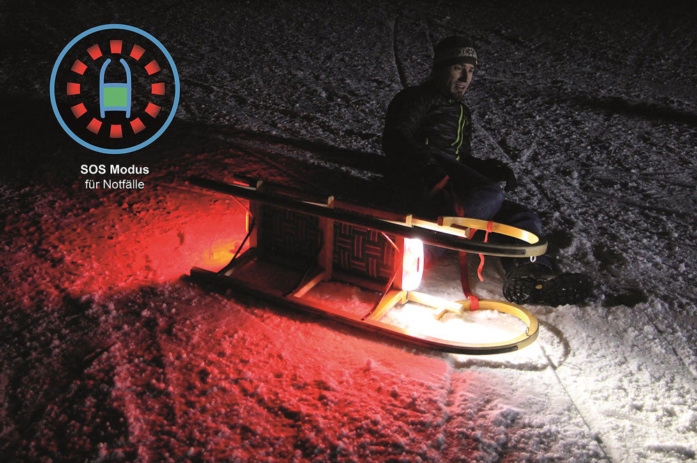 Mann neben Rodel mit Kathrein SLED Schlitten Beleuchtung Set „Style“ – Mobiles Rodellicht, seitlich, beleutet