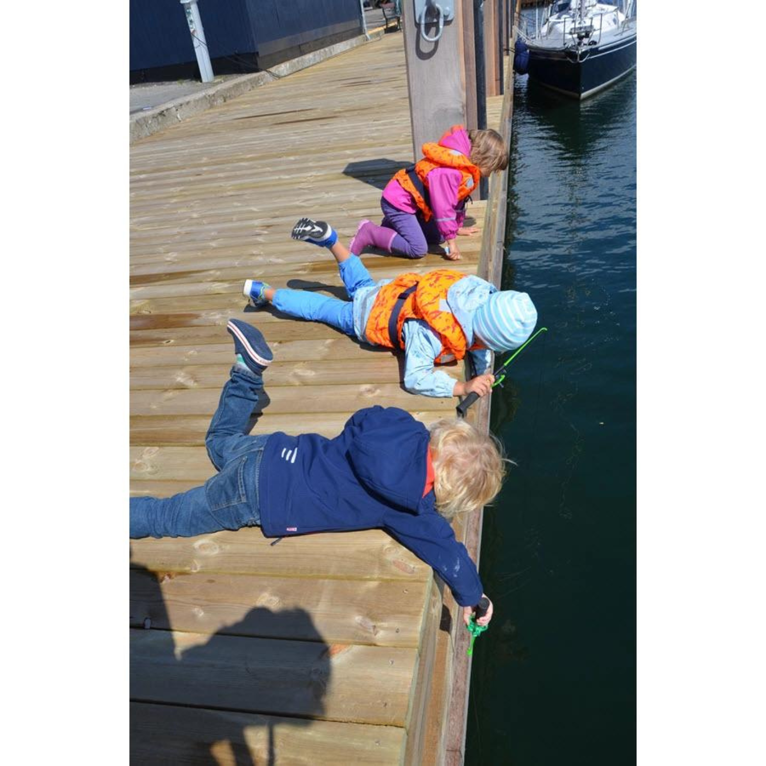 Kinder mit Secumar Bravo Print Kinder Schwimmweste auf Steg liegend