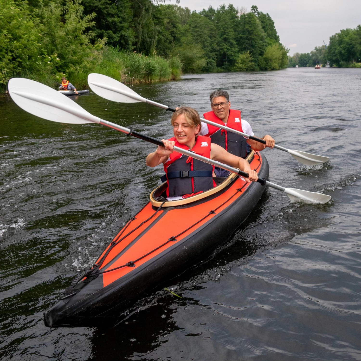 Zwei Menschen mit Secumar Echo Schwimmhilfe/ Kajakweste blau/ rot in zweier Kajak