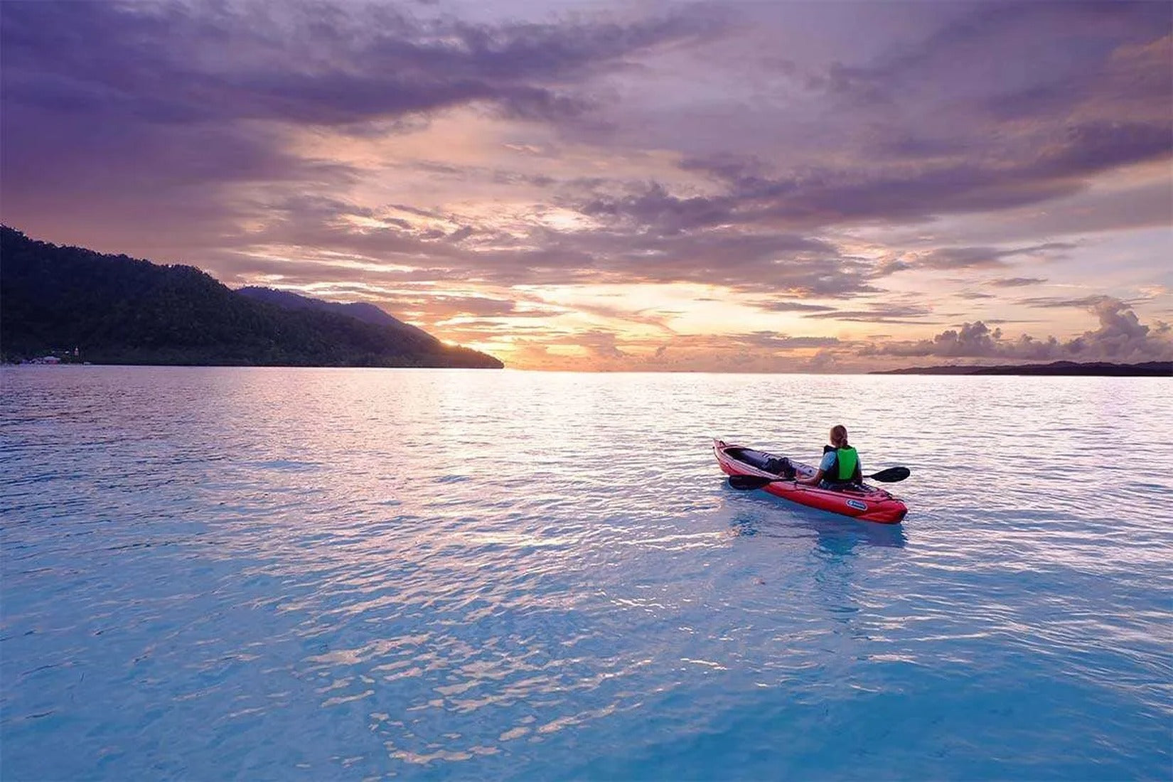 Person mit Gumotex Seawave Seekajak 1-3 Personen – Aufblasbares Schlauchboot, rot, auf dem Wasser