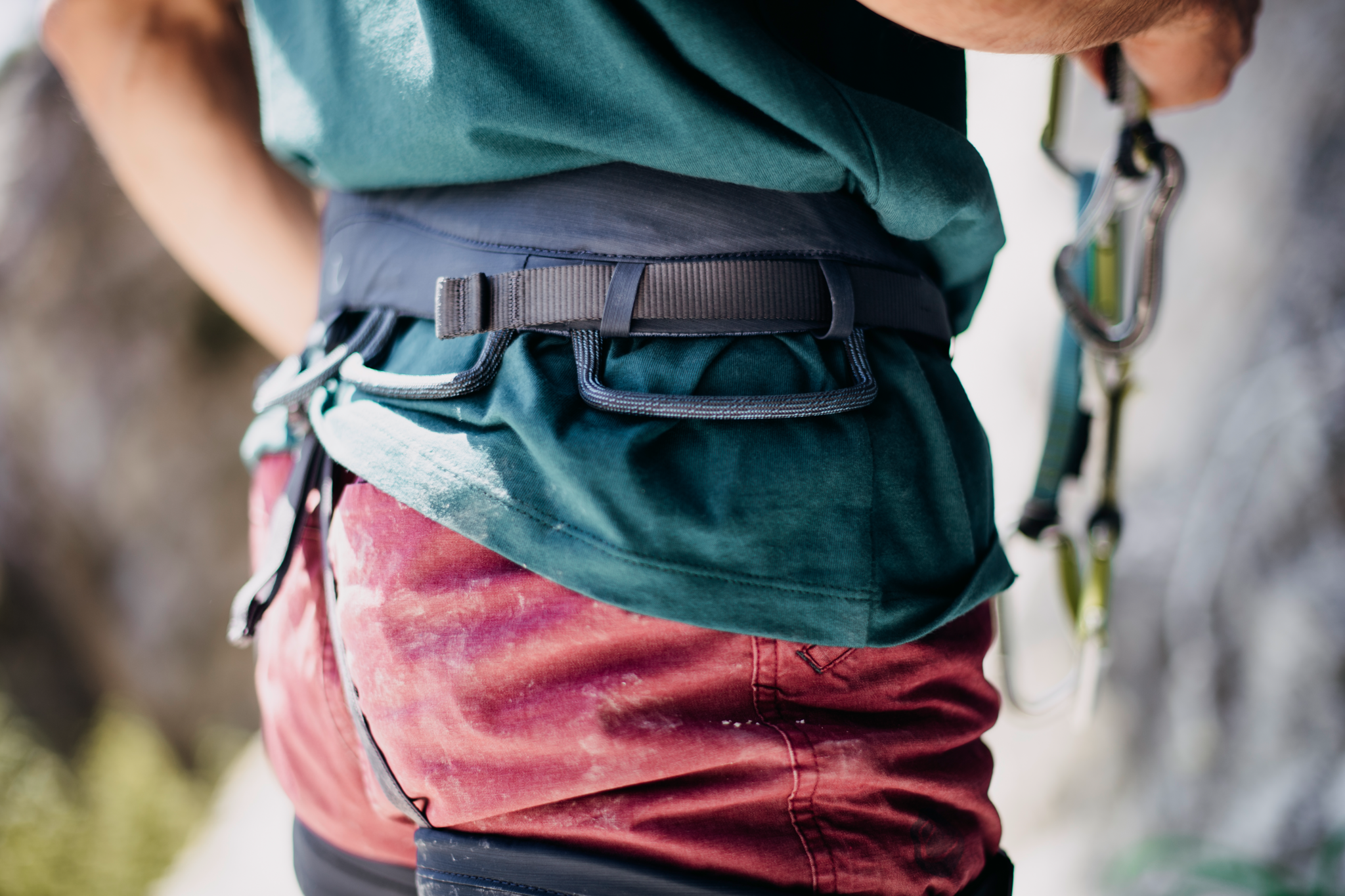 Person an Felswand stehend mit Edelrid Sendero Hüftgurt Damen und Herren, dunkelblau (lapis), mit Expressen in der Hand